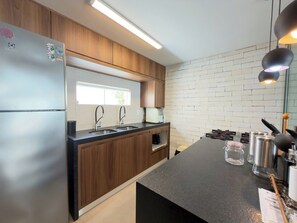 A modern kitchen with wooden cabinets, stainless steel appliances, and a black countertop.