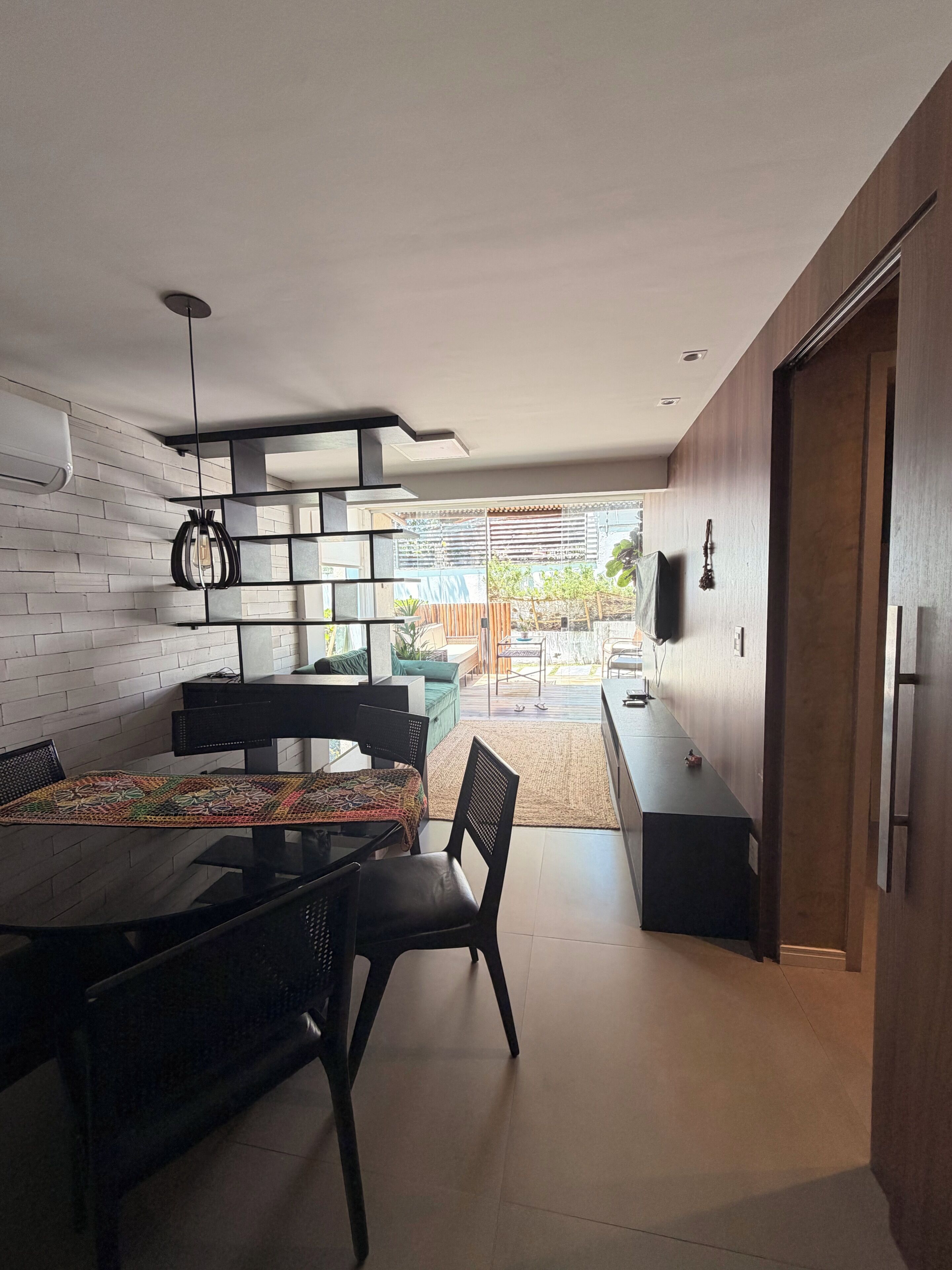 A modern dining area with a glass table, black chairs, and a patterned table runner.