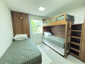 A compact bedroom with a bunk bed, a single bed, and a wooden wardrobe.