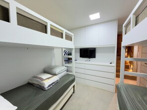 A bunk bed room with a television on a shelf, a desk, and a chair.