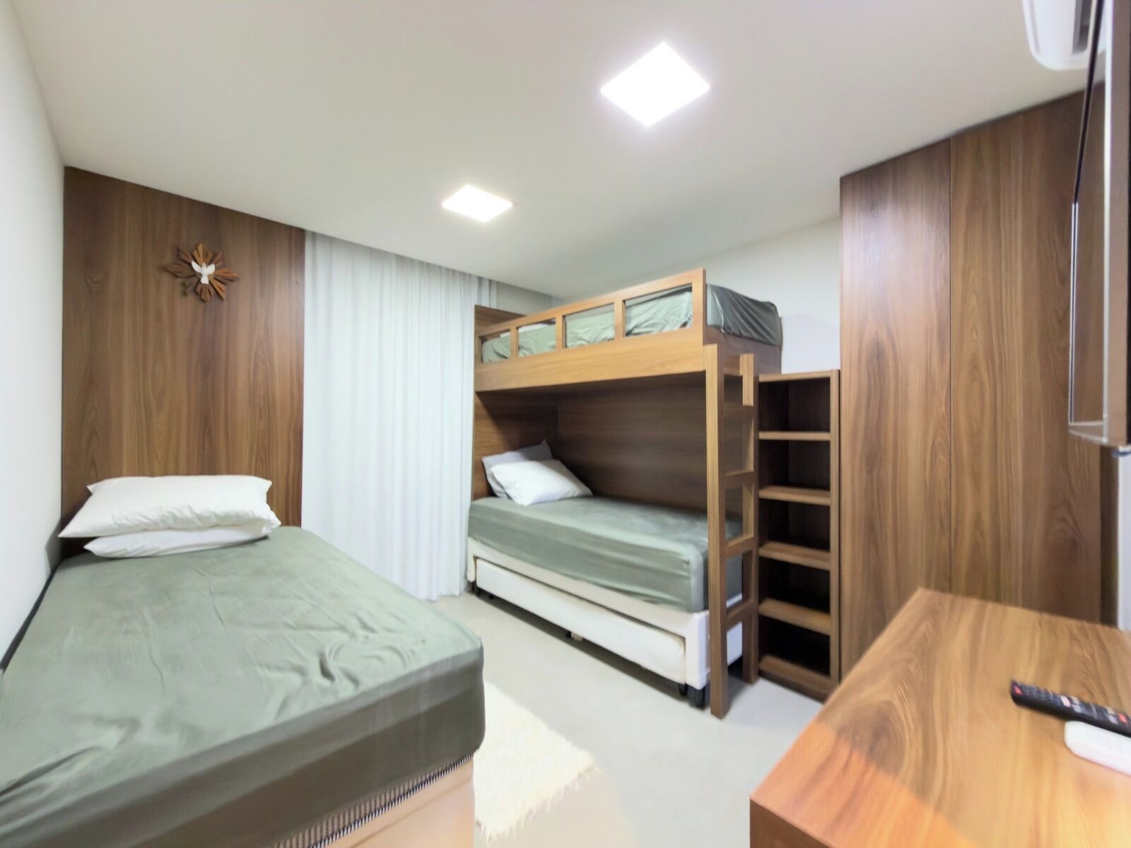 Quarto com cama beliche, uma cama de solteiro, escrivaninha e guarda-roupa.