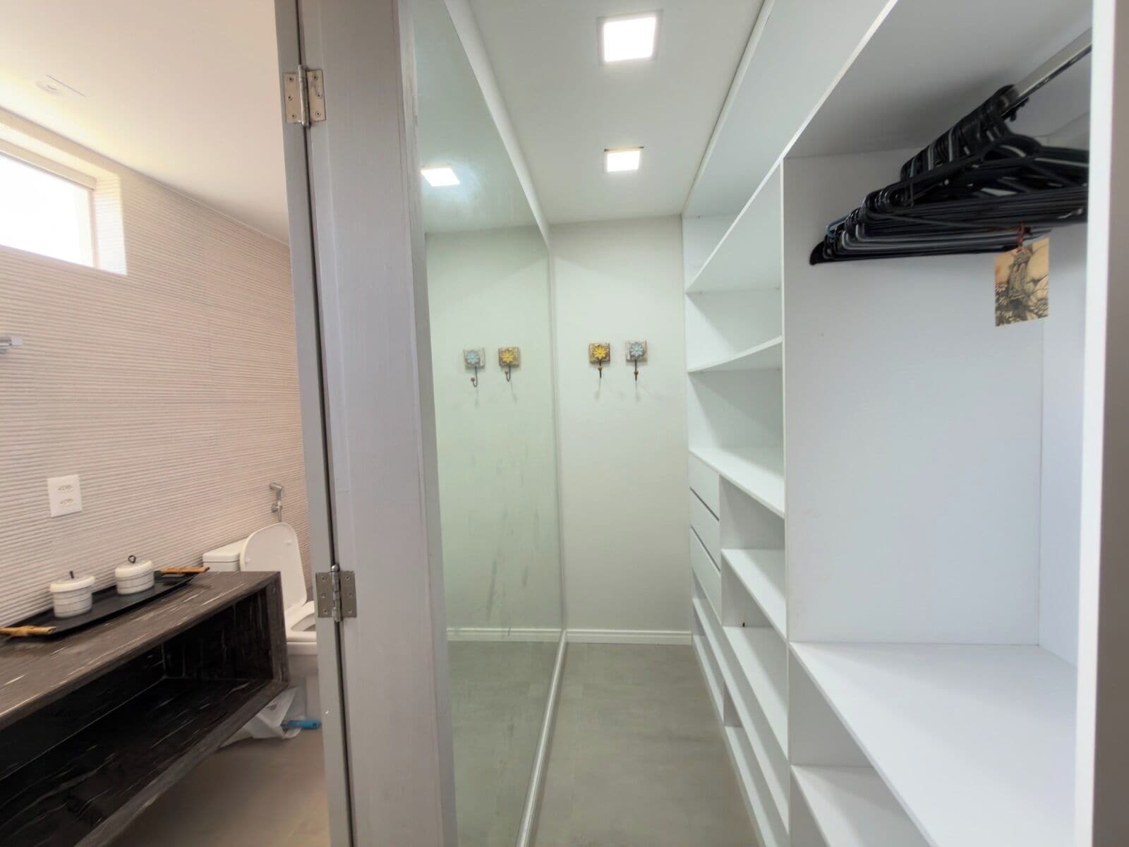 A modern bathroom with a toilet, a vanity with storage, and a glass shower enclosure.