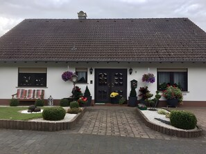 A two-story building with a tiled roof, a front door, and a bench outside.