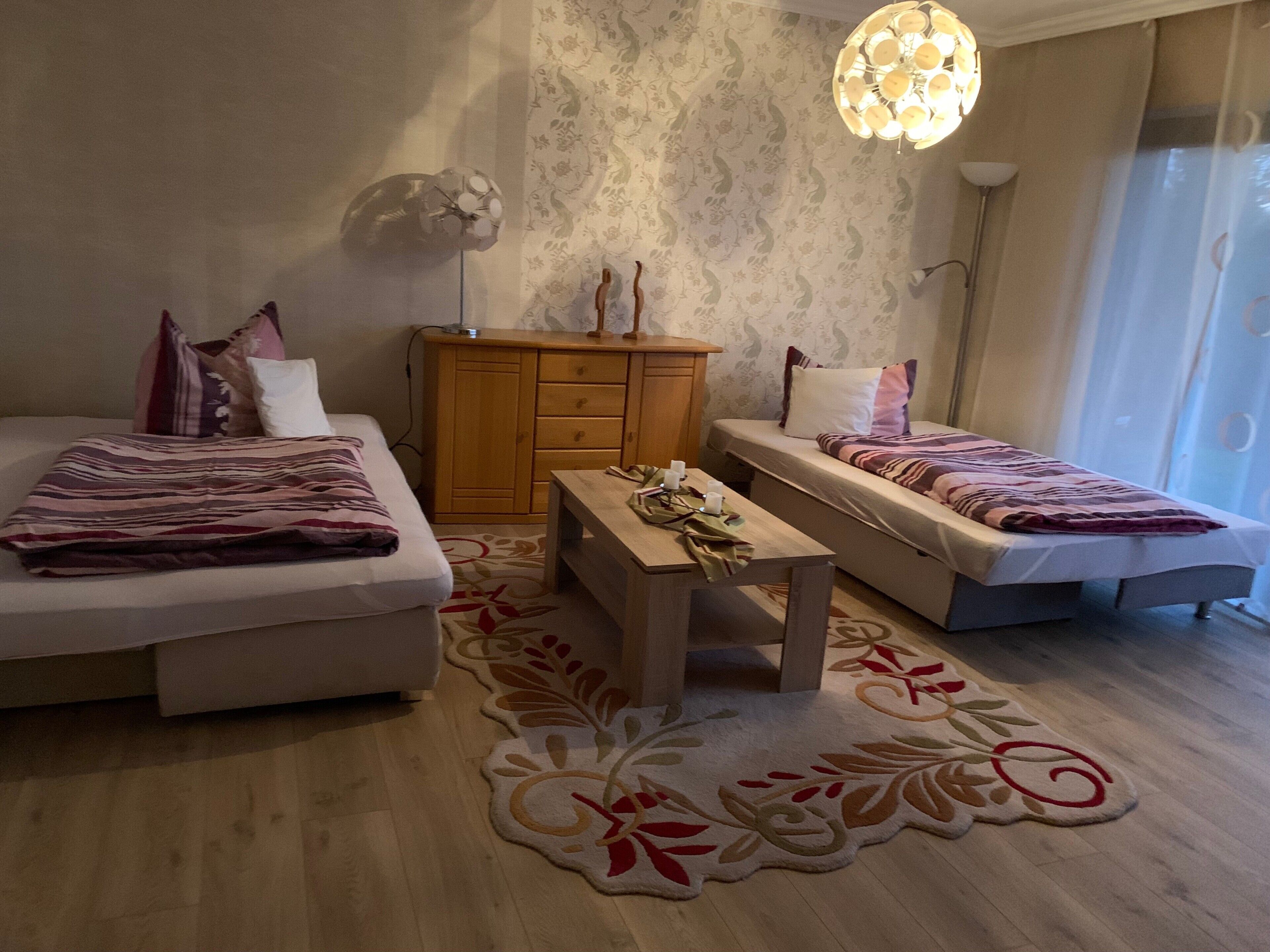 Un dormitorio con dos camas, un aparador de madera, una mesita y un tapete decorativo.