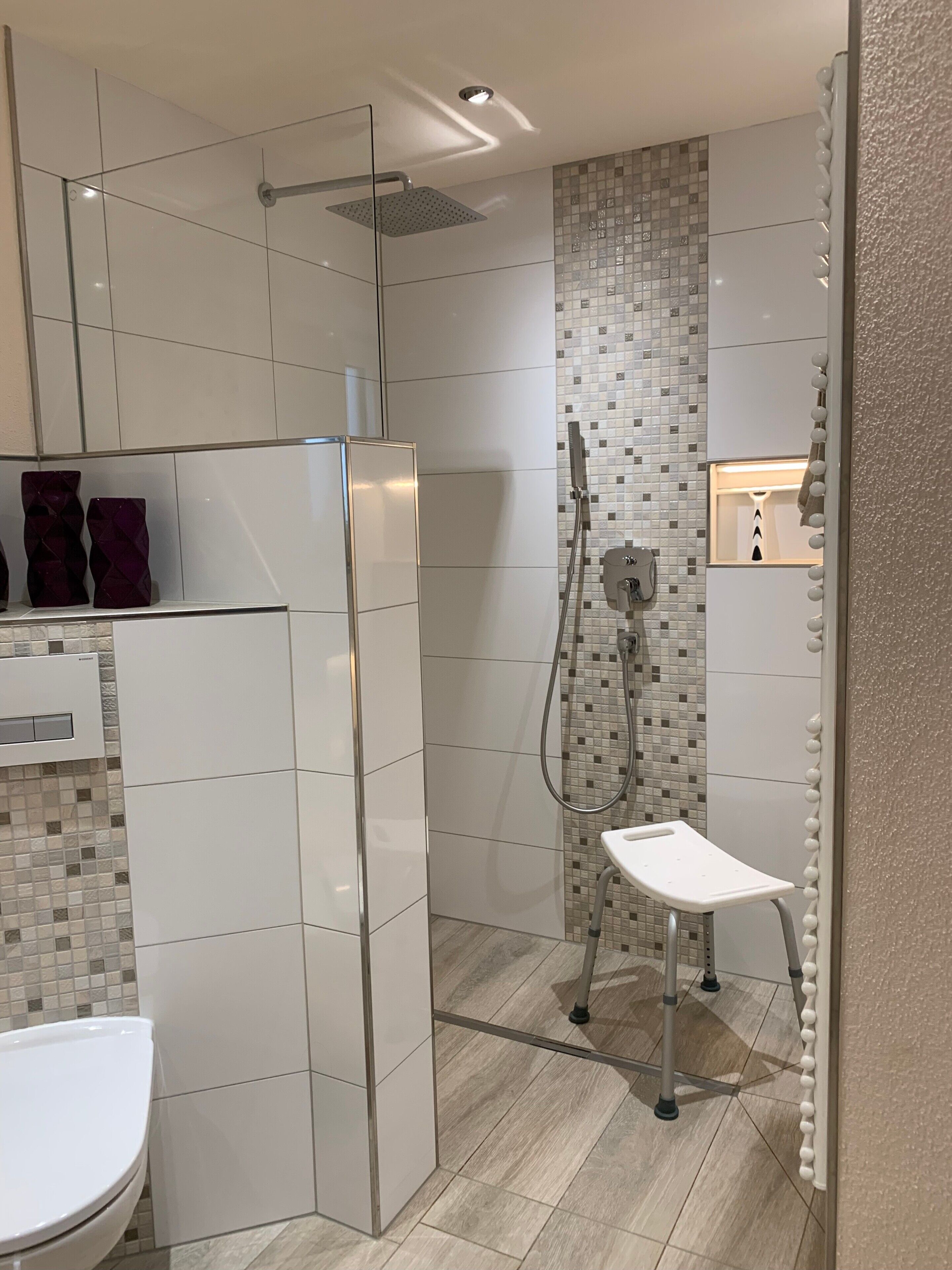 Une salle de bain moderne équipée d’une douche, de toilettes et d’un meuble-lavabo.