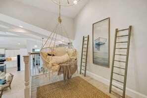 A spacious room with a hanging chair, a ladder, and a painting on the wall. - Silver Surf- A stunning family home 2 blocks from the beach. (Holmes Beach)