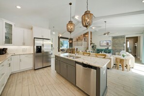 A modern kitchen with stainless steel appliances, a large island, and pendant lighting. - Silver Surf- A stunning family home 2 blocks from the beach. (Holmes Beach)