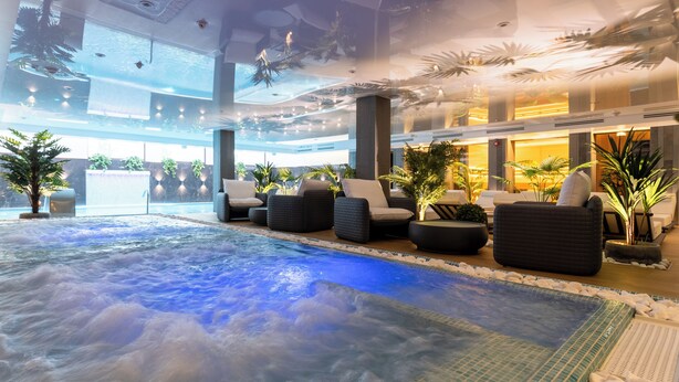 A heated indoor pool area with seating and plants.