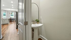 A hallway leading to a kitchen and bathroom with a white sink and a plant. - Casa Azul at the Cape - a family friendly 5-bedroom paradise! (Cape Coral)