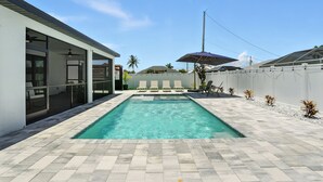 A swimming pool with a tiled deck, a covered seating area, and a white fence. - Casa Azul at the Cape - a family friendly 5-bedroom paradise! (Cape Coral)