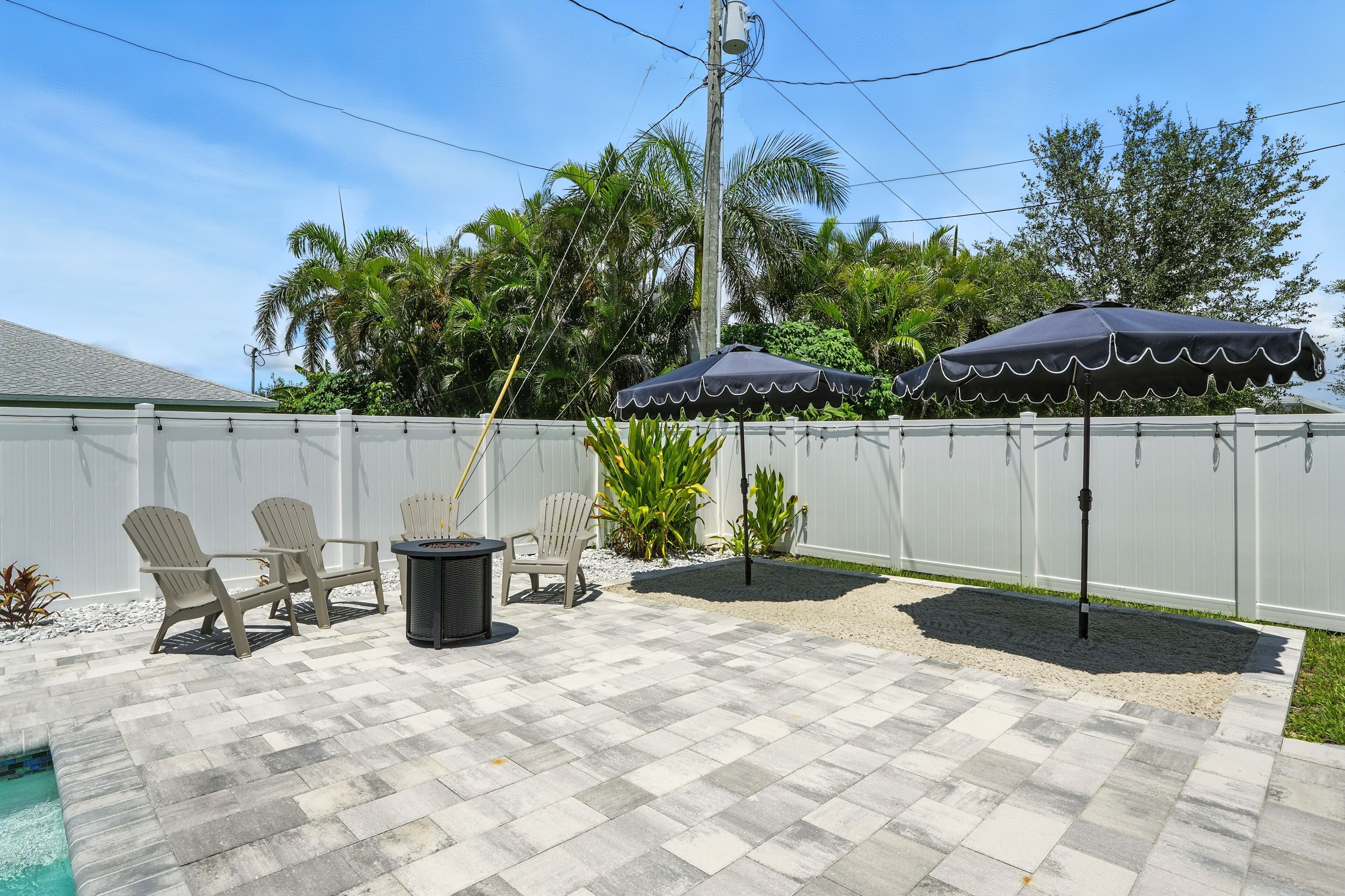 An outdoor patio with a pool, chairs, and umbrellas.