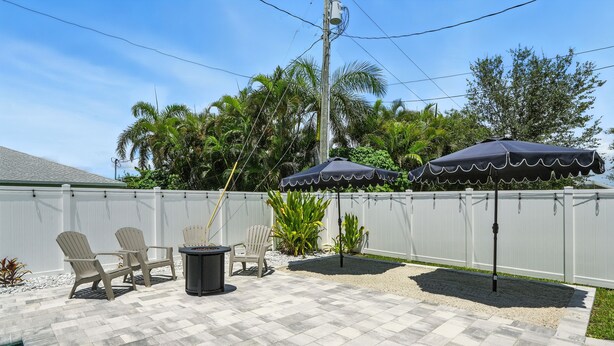 An outdoor patio with a pool, chairs, and umbrellas. - Casa Azul at the Cape - a family friendly 5-bedroom paradise! (Cape Coral)