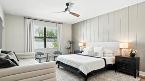 A modern bedroom with a bed, bedside tables, a desk, a chair, and a ceiling fan. - Casa Azul at the Cape - a family friendly 5-bedroom paradise! (Cape Coral)