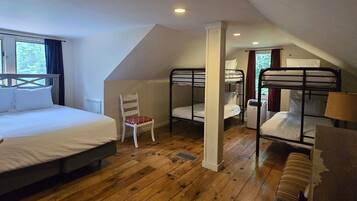 A room with a bunk bed, a single bed, a chair, and a window.