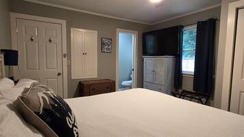 Une chambre à coucher avec un lit, un ventilateur de plafond, une armoire et une fenêtre.