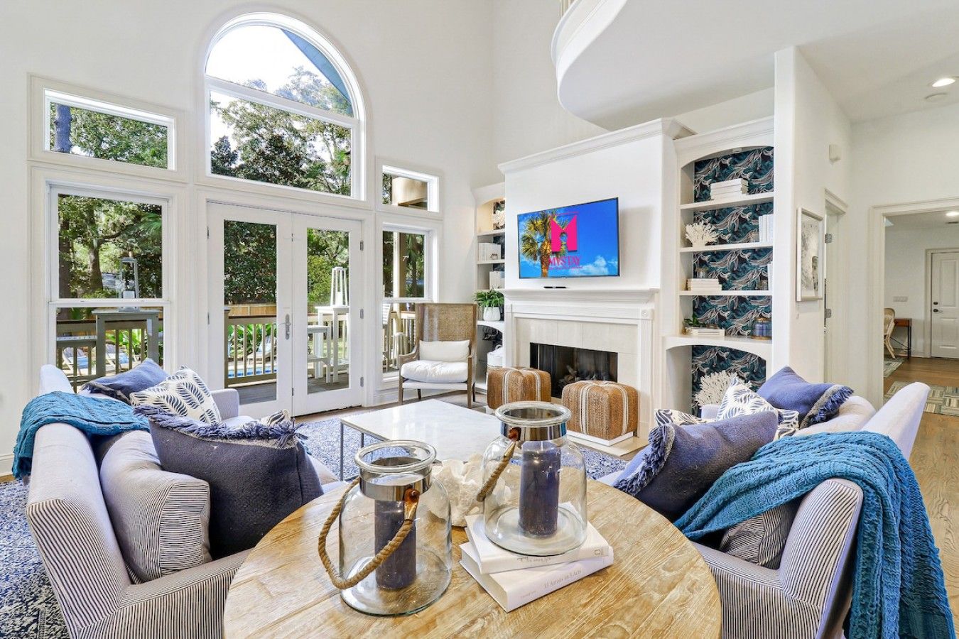 Un salón amplio con chimenea, televisor montado arriba y un gran ventanal con vistas al exterior.