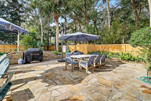 An outdoor patio with stone flooring, a barbecue grill, and a table with chairs. - MyStay @ 3 Myrtle | 3 Min to Beach | Private Pool | Sleeps 20 (Hilton Head Island)