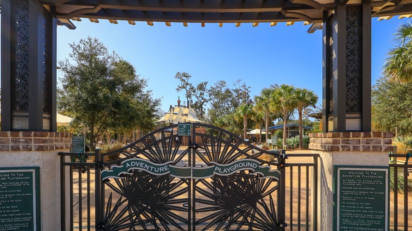 A gated entrance to a playground with a sign indicating it is for children under 13.