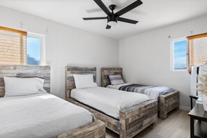 Ein Schlafzimmer mit zwei Betten, einem Deckenventilator und einem Fenster mit Vorhängen.