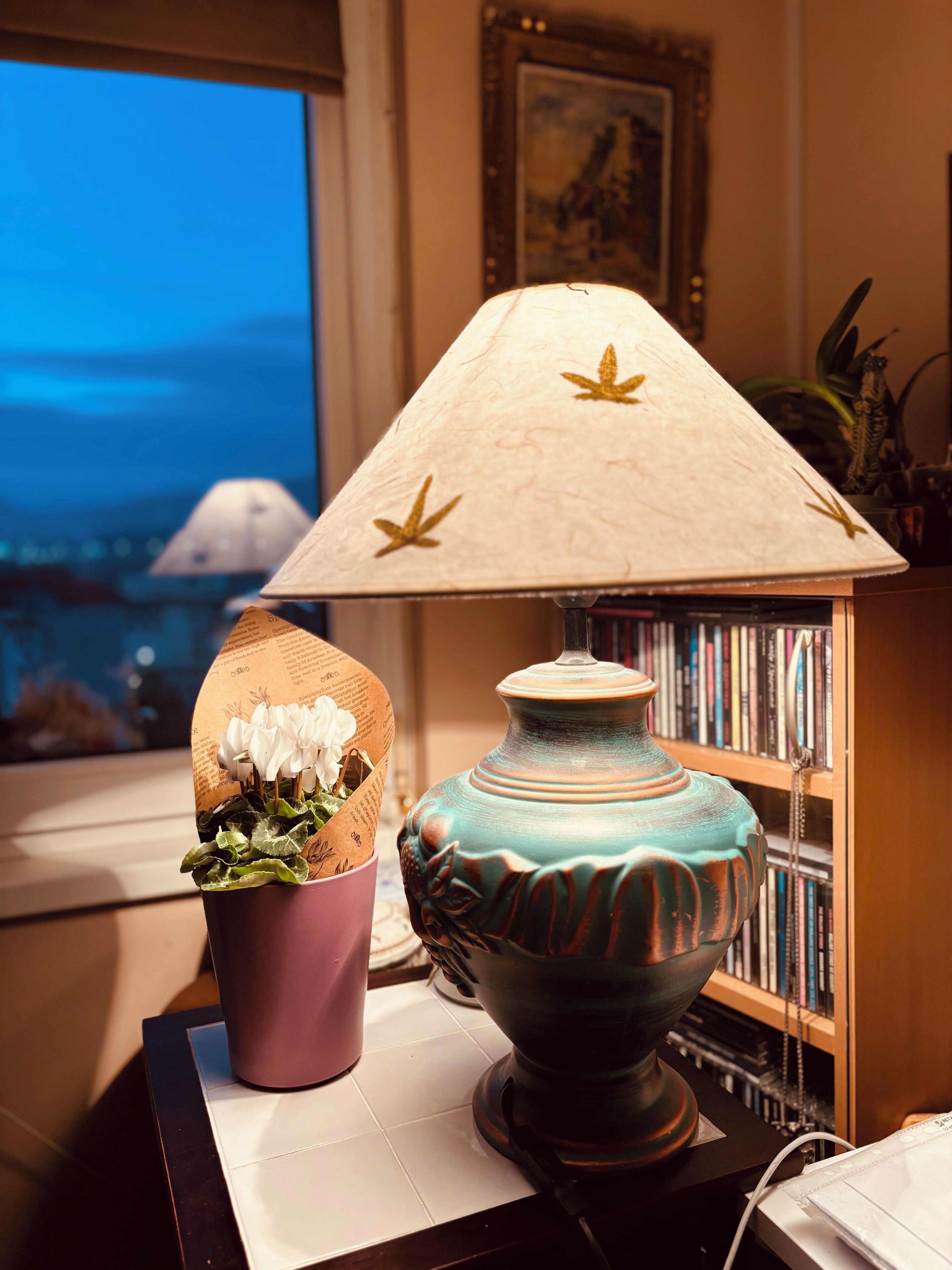 Una lámpara con pantalla cónica y un florero de superficie texturizada sobre una mesa.