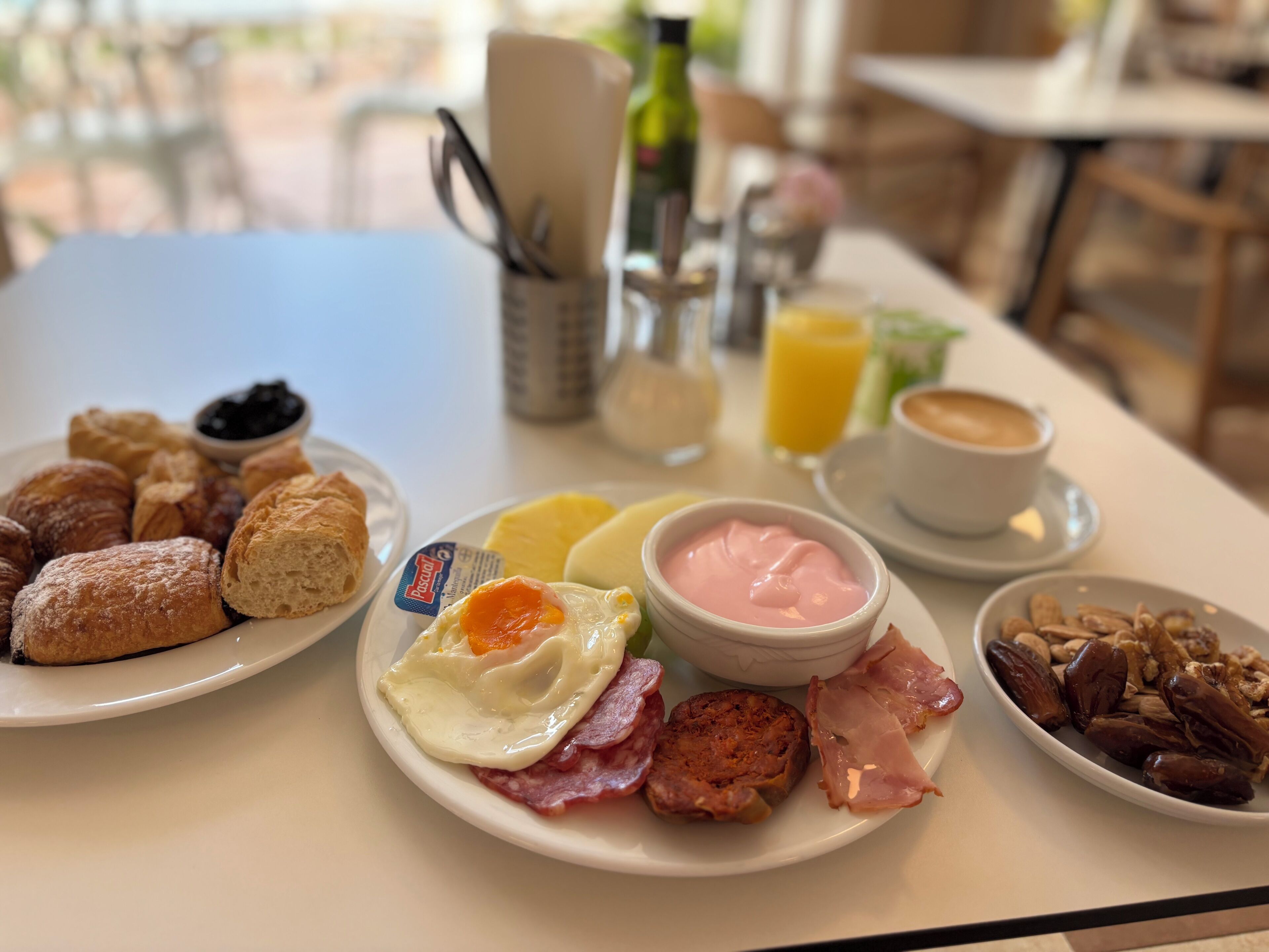 Ein Frühstückstisch mit Tellern voller Gebäck, Eiern, Schinken und Datteln.