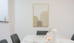 A conference room with a marble table, chairs, a vase with flowers, and a framed abstract painting on the wall. - MetaWiseBnB 2BR Near Airport Parking Sleeps 6 (Mascot)