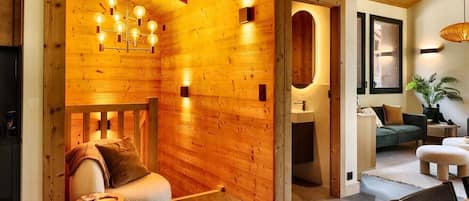 Un interior acogedor con pared de madera, una lámpara moderna, un sofá, una mesa de comedor y una planta.