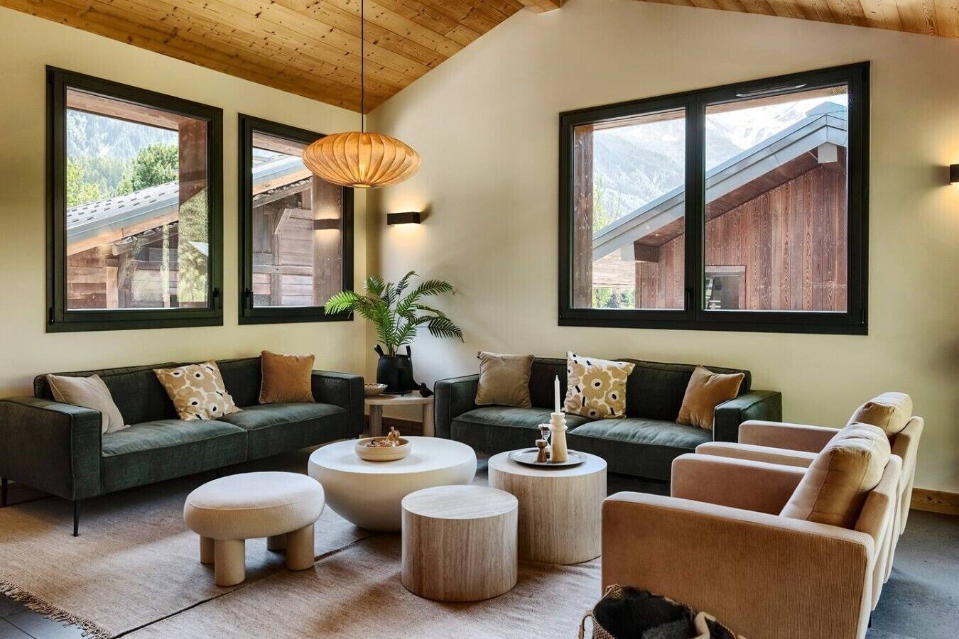 A modern living room with a sofa set, round coffee tables, and a hanging light fixture.