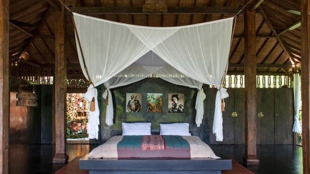 Una cama con dosel, vista al exterior y una obra de arte en la pared.