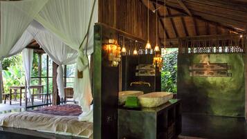A bedroom with a canopy bed, a stone sink, and a wooden ceiling.