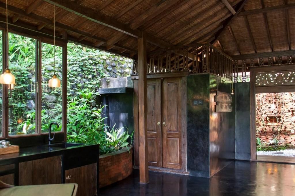 Una habitación con techo de madera, pared de piedra y puerta de madera.