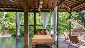 Una habitación con cama, una silla y vista al exterior.