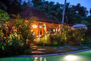 A tropical resort with a pool, a covered outdoor seating area, and lush vegetation. - Villa Mahadevi (Gianyar)