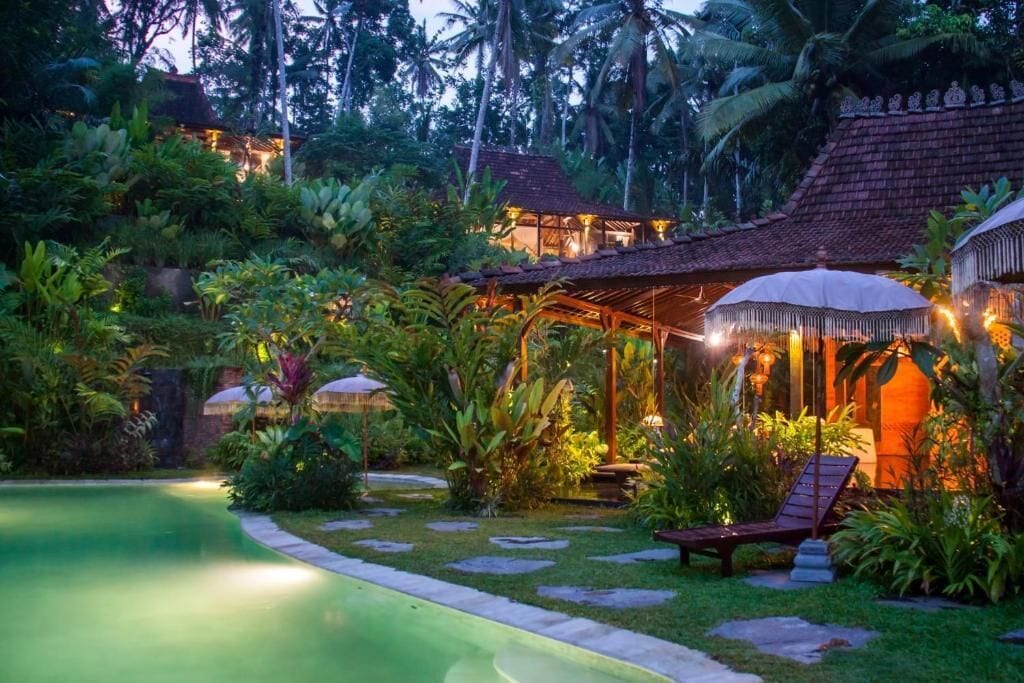 Un resort tropical con piscina, estructuras de techo de paja y exuberante vegetación.