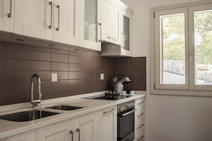 A kitchen with a double sink, a stove, and a window. - Villa Idylle | Ithaca Greece (Ithaki)