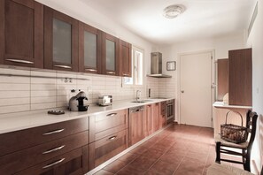 A modern kitchen with wooden cabinets, a coffee machine, and a toaster. - Villa Idylle | Ithaca Greece (Ithaki)