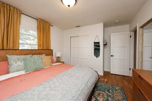 A bedroom with a bed, a nightstand, a wall-mounted lamp, a door, and a small rug. - The Sunny Casita + Zoo + Spa + Views + Downtown (San Diego)