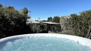 Una vasca idromassaggio esterna circondata da alberi e un edificio sullo sfondo.