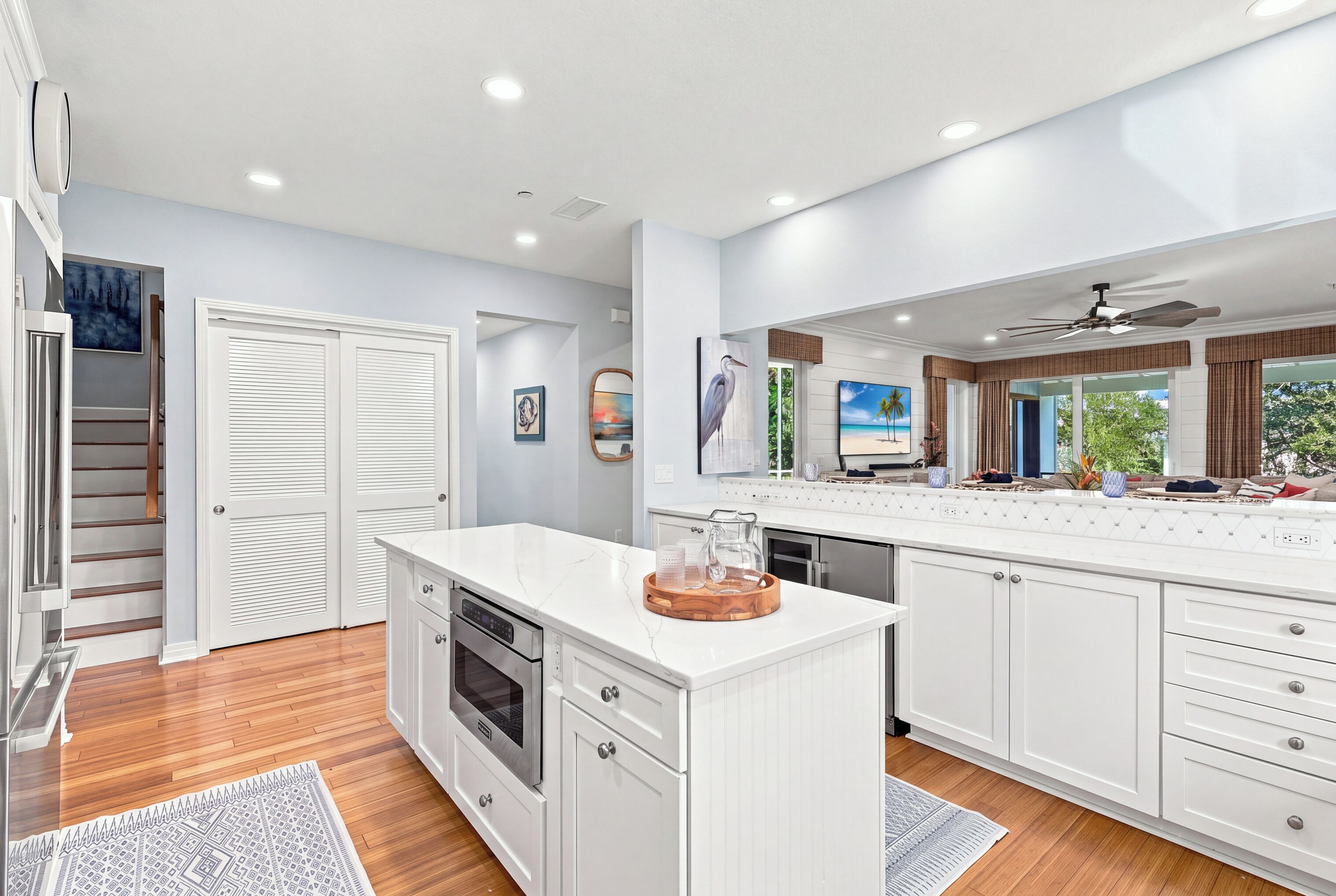 A modern kitchen with white cabinetry, a central island, and a view of the outdoors.