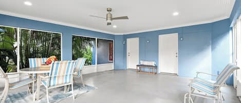 Une pièce spacieuse dotée d’un ventilateur de plafond, d’une table à manger avec des chaises et d’un banc.