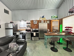A compact kitchen with a refrigerator, stove, and microwave. There is a dining area with a table and chairs.