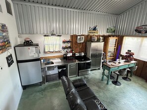 A compact kitchen with a refrigerator, stove, sink, and a dining area with a table and chairs.