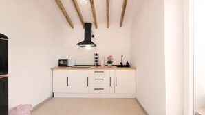 A compact kitchen with white cabinetry, a black range hood, a countertop with a toaster, and a pink trash bin. - El Patio de Rafaela Country House with Mountain Views, Wi-Fi and Air Conditioning (Alcaucín)