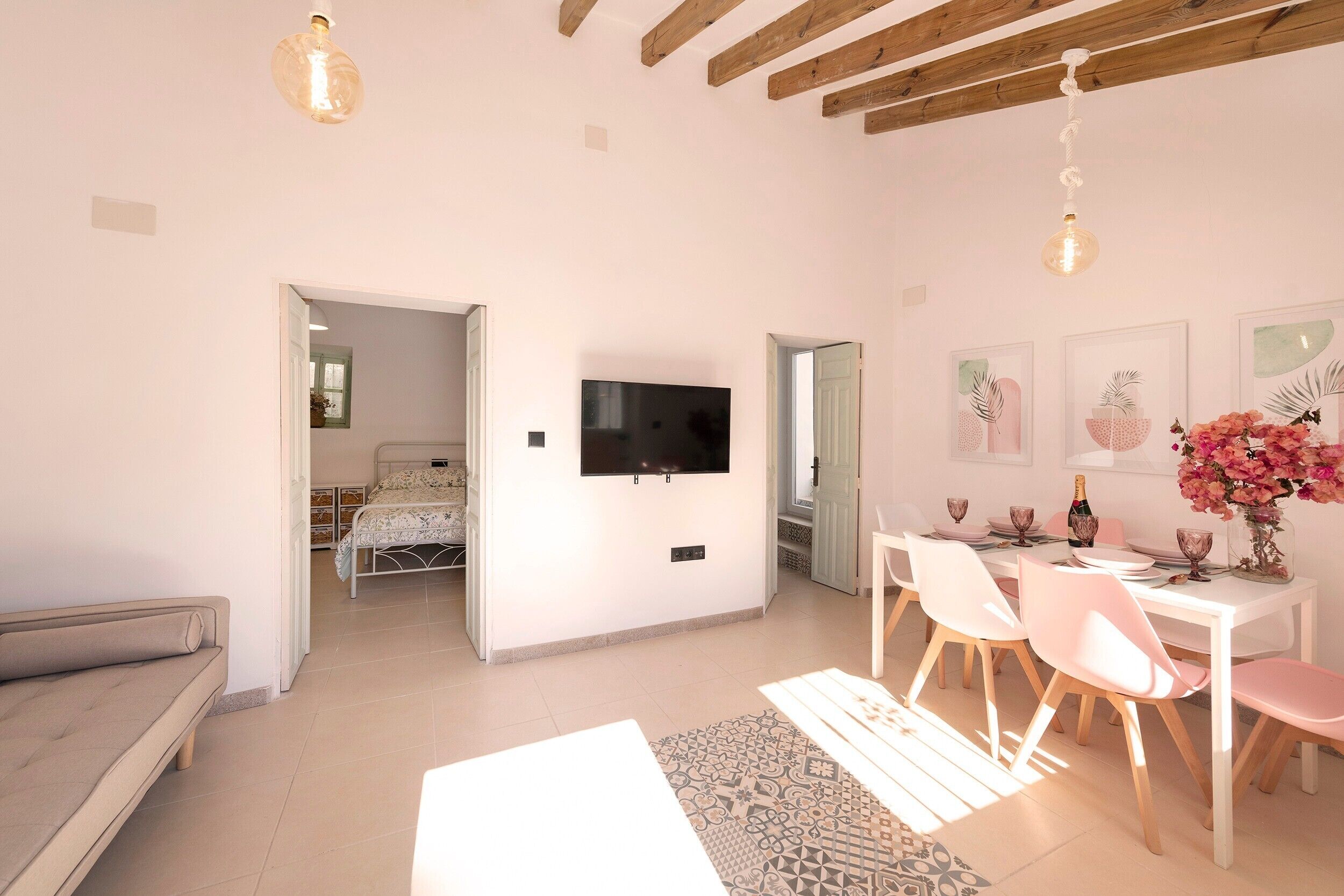 Un vaste espace de vie comprenant un téléviseur à écran plat fixé au mur, une table à manger avec des chaises et un canapé.