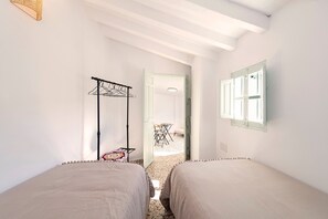 A room with two beds, a drying rack, a table with chairs, and a window with a view. - El Patio de Rafaela Country House with Mountain Views, Wi-Fi and Air Conditioning (Alcaucín)