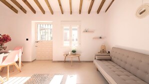 A living room with a sofa, a dining table with chairs, a small table with a plant, and a wall-mounted shelf. - El Patio de Rafaela Country House with Mountain Views, Wi-Fi and Air Conditioning (Alcaucín)