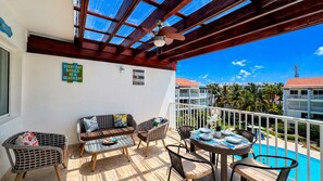 Ein Balkon mit Korbmöbeln, ein Pool und Blick auf andere Gebäude.