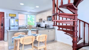 Eine moderne Küche mit Essbereich, einer Holztreppe und Blick ins Freie.