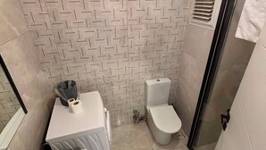 Un baño con salpicadero de azulejos estampados, inodoro, lavabo y zona de ducha.