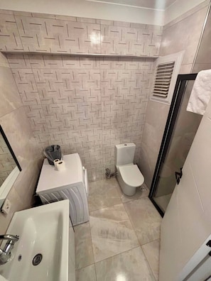 A bathroom with a patterned tile backsplash, a toilet, a sink, and a shower area.